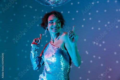 Young happy woman posing isolated with disco ball lights.