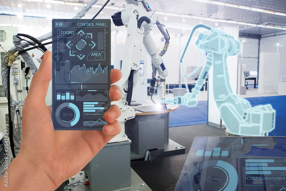 Engineer uses a futuristic transparent smartphone to control robots in a smart factory. Smart industry 4.0 concept. Engineer uses a futuristic transparent smartphone to control robots in a smart factory. Smart industry 4.0 concept.