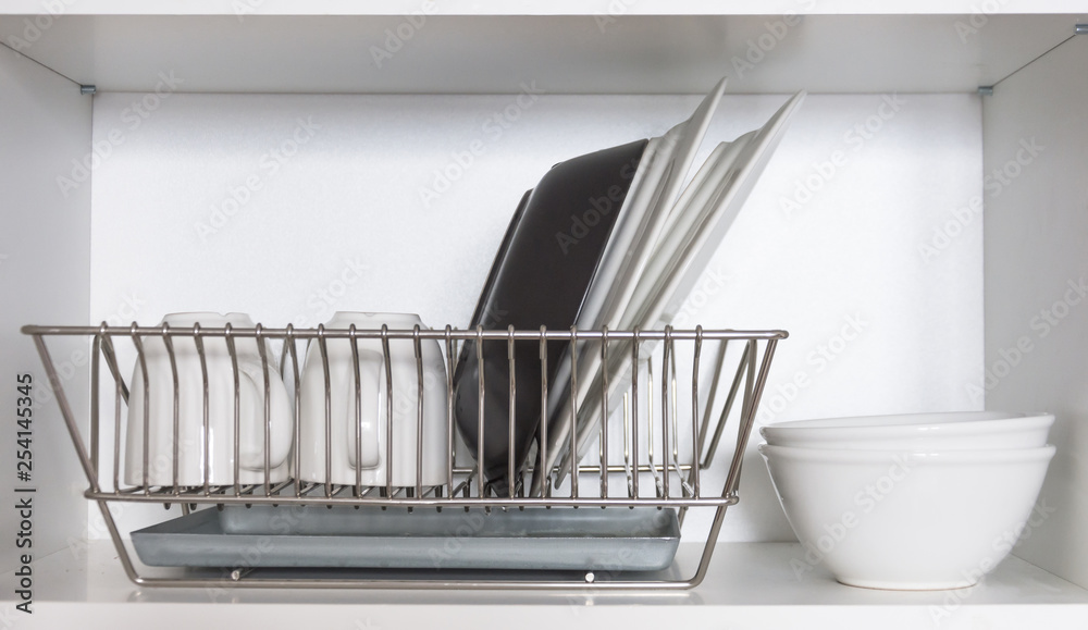 Kitchen cupboard with a lattice for dishes, with a white and black plate, cups, and a drip tray Kitchen cupboard with a lattice for dishes, with a white and black plate, cups, and a drip tray