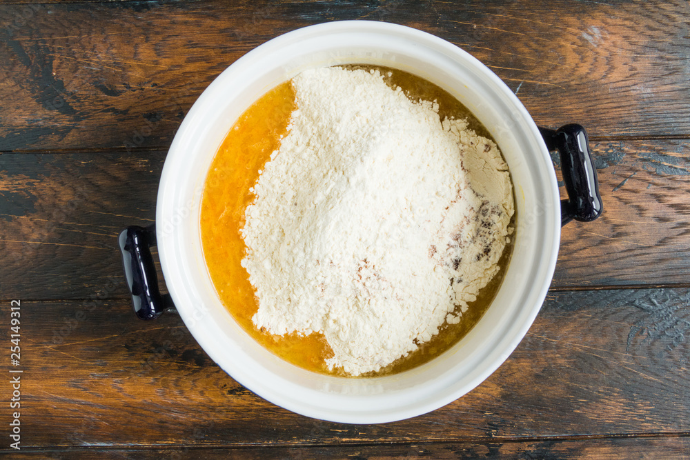 Dough making, olive oil, sugar, orange juice and zest, flour in white bowl. Wooden rustic table, top view Dough making, olive oil, sugar, orange juice and zest, flour in white bowl. Wooden rustic table, top view