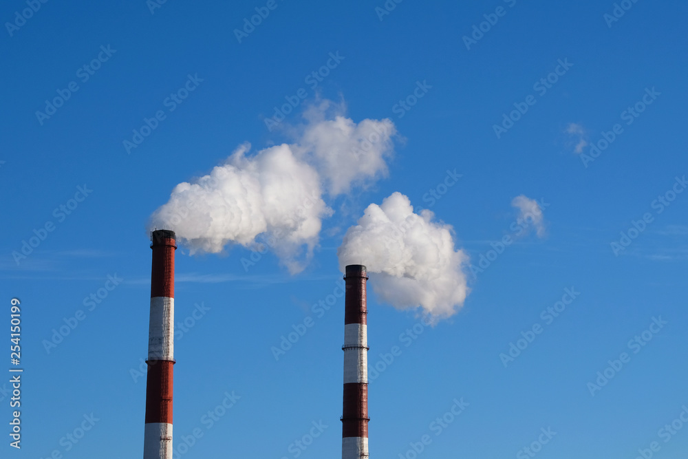 Environmental problem of environmental pollution and air in large cities. Pipes in city with smoke, against a blue sky background.