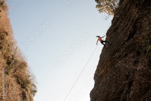 Strong woman equipped with a rope abseiling on the sloping rock