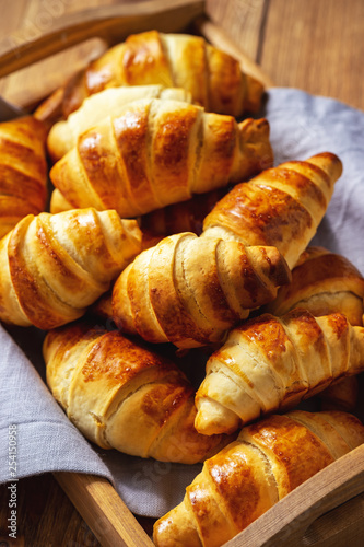 Homemade butter croissants on wooden tray.