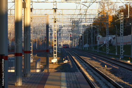 the train arrives at the railway platform in the sun at sunset