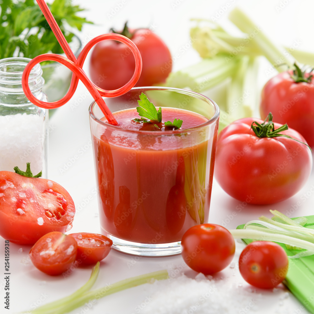 Tomato juice in glass. Tomato juice in glass with celery, cherry tomato, white wood background, closeup Tomato juice in glass. Tomato juice in glass with celery, cherry tomato, white wood background, closeup