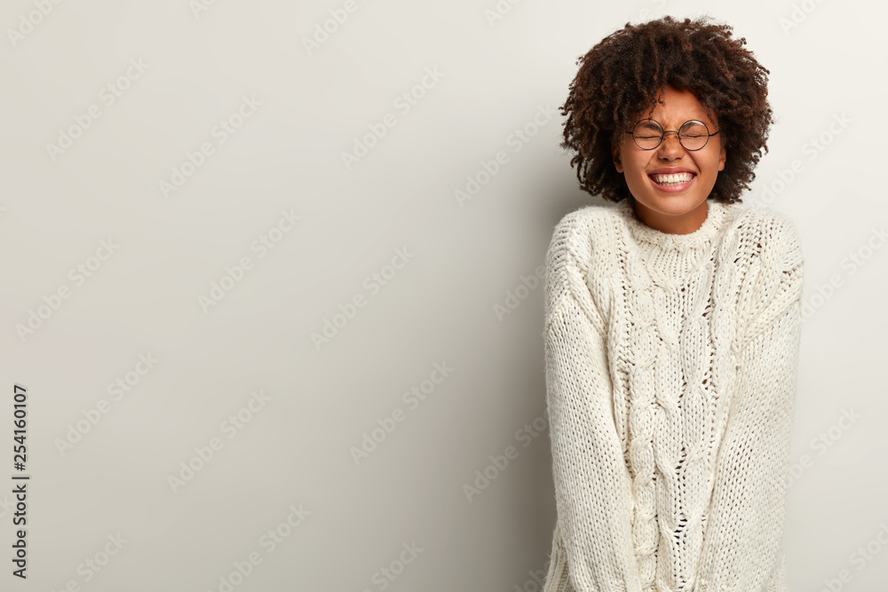 Portrait of carefree upbeat lady with dark skin laughs positively, enjoys cool party, squints face and shows perfect teeth, wears casual clothes, isolated over white background, amused by someone Portrait of carefree upbeat lady with dark skin laughs positively, enjoys cool party, squints face and shows perfect teeth, wears casual clothes, isolated over white background, amused by someone