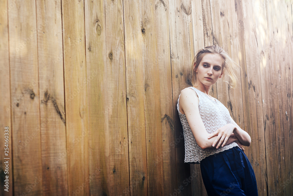 Naklejka premium Attractive girl at wooden fence with the sun's rays.