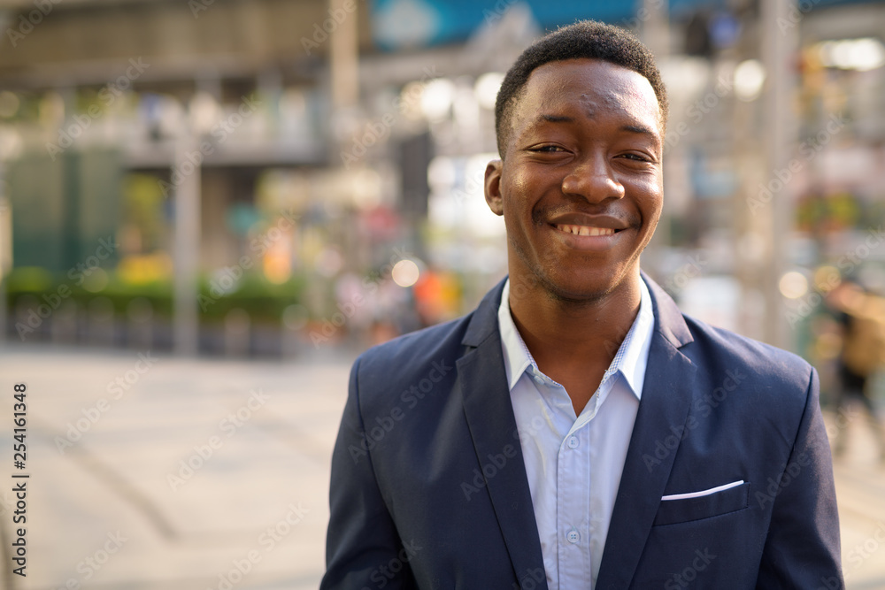 Face of young happy African businessman smiling in the city Face of young happy African businessman smiling in the city