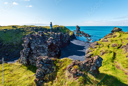 Girl Teenagers staying in the top of the lava rock observing the landscape of Djupalonssandur beach in Icelandic Snaefellsjokull National Park.