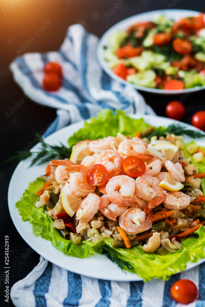 Closeup of fried shrimp and vegetables on plates on black background Closeup of fried shrimp and vegetables on plates on black background