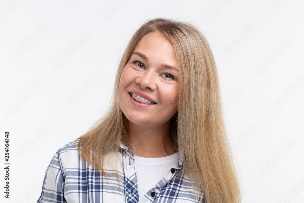 Teeth health, dentistry and bite correction - Happy smiling woman with braces on white background Teeth health, dentistry and bite correction - Happy smiling woman with braces on white background