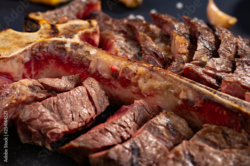 porterhouse t-bone steak is grilled sliced on a piece on black background. rustic style, top view