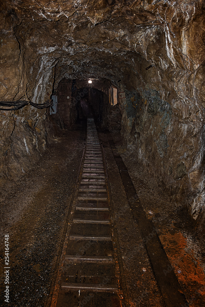 Fototapeta premium Empty old abandoned mine shaft with rusty railway