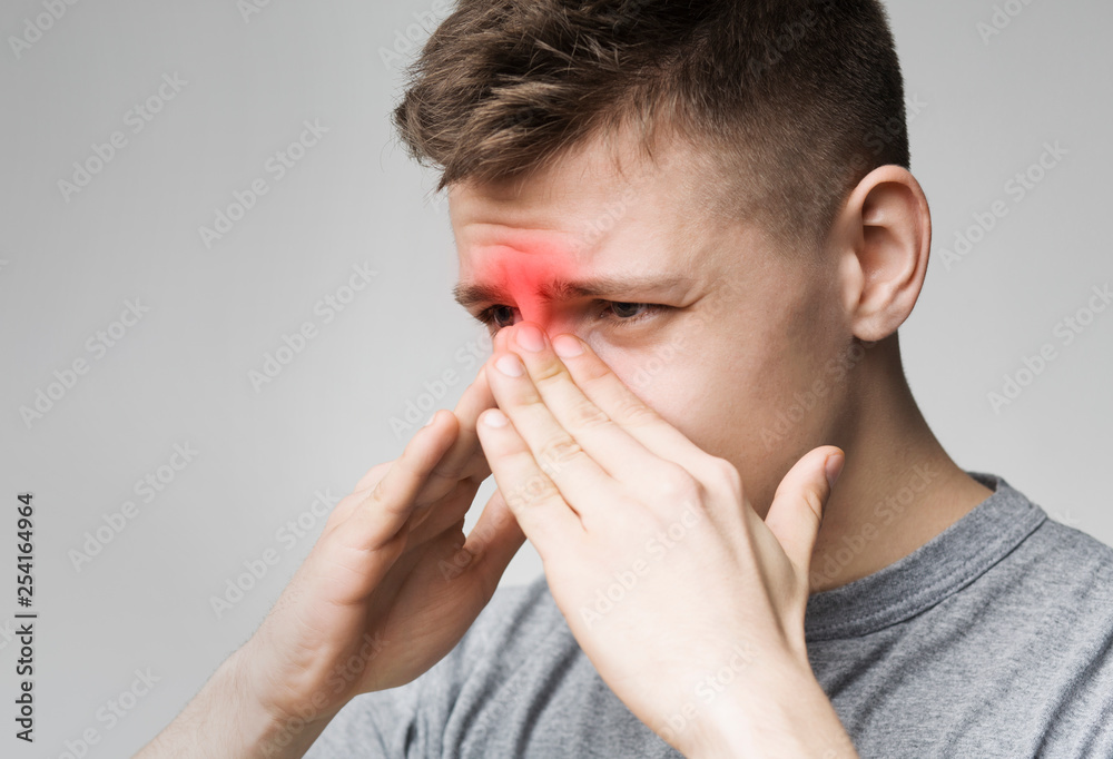 Sad man holding his nose because sinus pain Sad man holding his nose because sinus pain