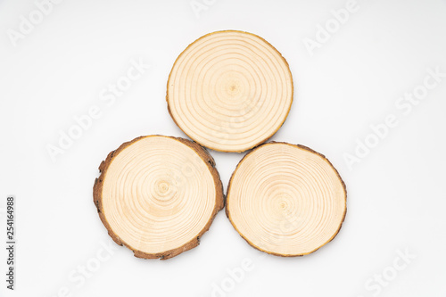 Fototapeta Naklejka Na Ścianę i Meble -  Three pine tree cross-sections with annual rings on white background. Lumber piece close-up shot, top view, isolated.