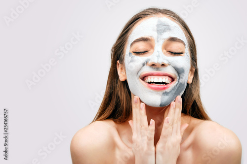 Beautiful laughing woman with gray clay facial mask