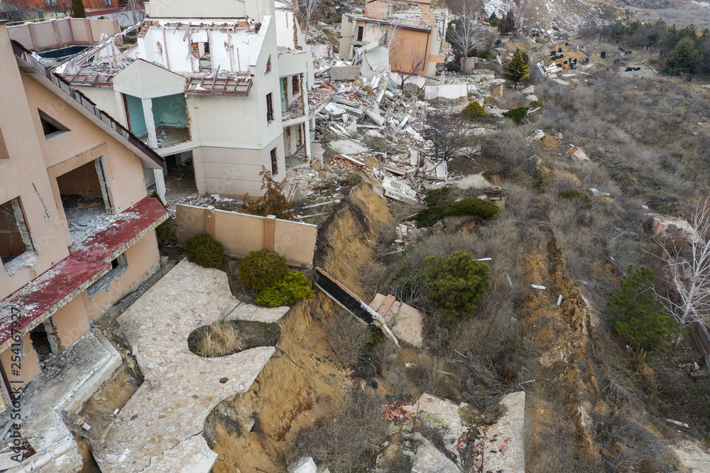 Landslide caused by rains of hurricane destroyed expensive cottages and houses. Destroyed house, cottage, large cracks, chips, slabs. Broken asphalt shifted landslide after earthquake. View from drone Landslide caused by rains of hurricane destroyed expensive cottages and houses. Destroyed house, cottage, large cracks, chips, slabs. Broken asphalt shifted landslide after earthquake. View from drone