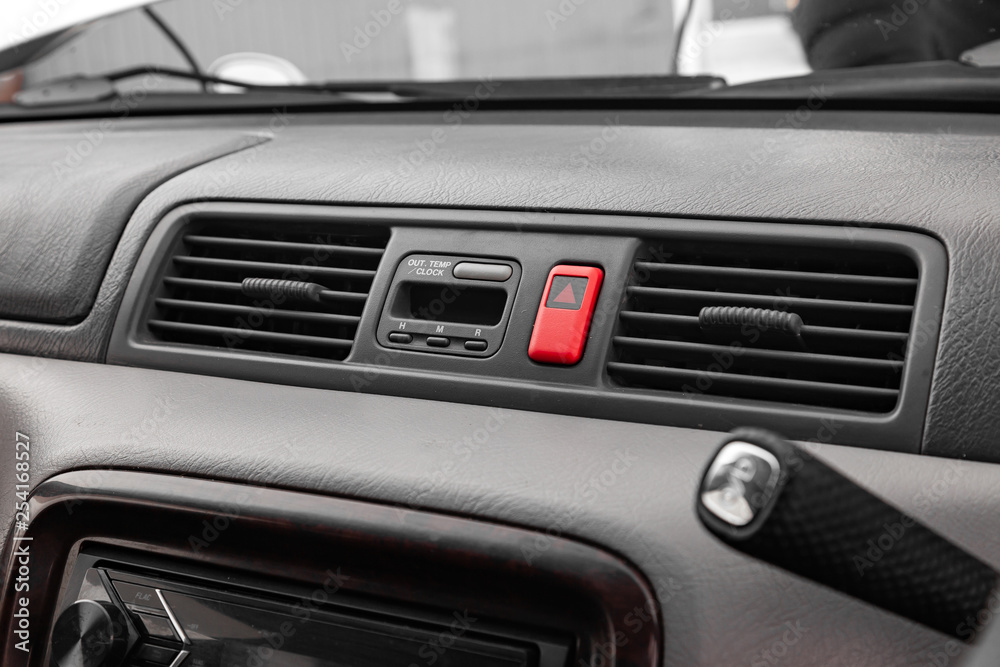 Close-up on emergency button in red color with clock near the duct in the interior of an old Japanese car in gray after dry cleaning Close-up on emergency button in red color with clock near the duct in the interior of an old Japanese car in gray after dry cleaning