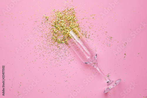 Champagne glasses with golden confetti on pink color paper background minimal style