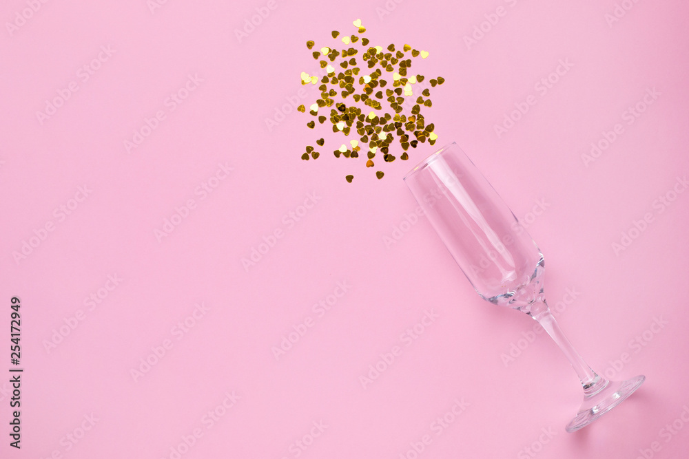 Champagne glass with golden confetti on pink color paper background minimal style Champagne glass with golden confetti on pink color paper background minimal style