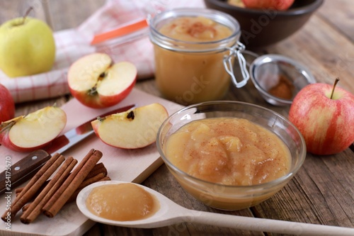 homemade apple jam, with fresh apples and spices with wooden spoon on wooden rustic table