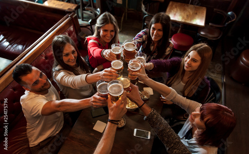 Obraz na płótnie group of people celebrating in a pub drinking beer