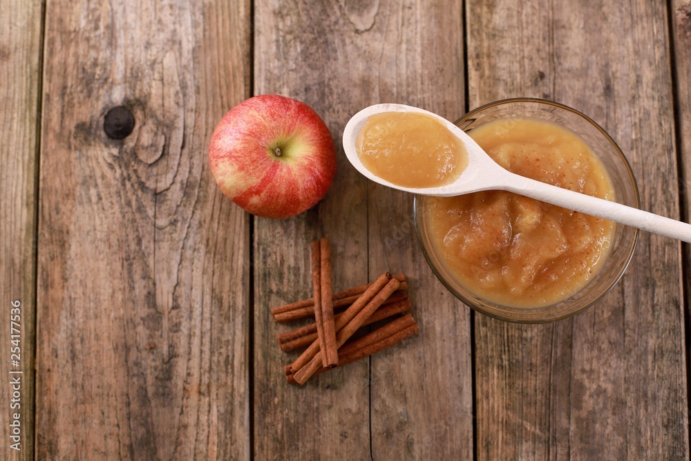 fresh homemade apple jam, apple puree with cinnamon in a bowl with wooden spoon and apples on wooden rustic table fresh homemade apple jam, apple puree with cinnamon in a bowl with wooden spoon and apples on wooden rustic table