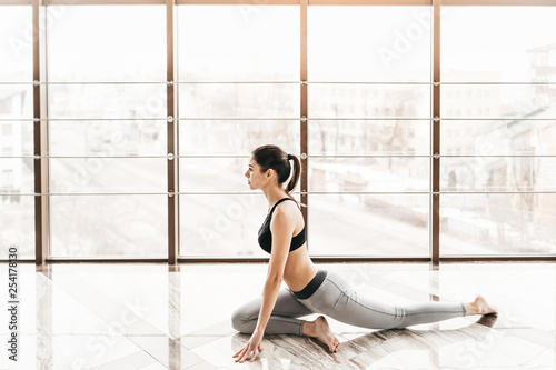 Young slim attractive woman with long hair practicing yoga indoors.