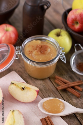 fresh homemade apple jam , apple puree, with cinnamon, fresh apples and a wooden spoon on wooden rustic table