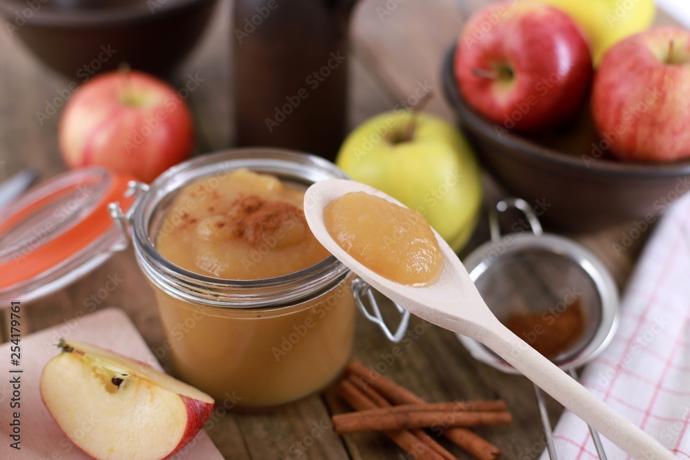 fresh homemade apple jam , apple puree, with cinnamon, fresh apples and a wooden spoon on wooden rustic table fresh homemade apple jam , apple puree, with cinnamon, fresh apples and a wooden spoon on wooden rustic table
