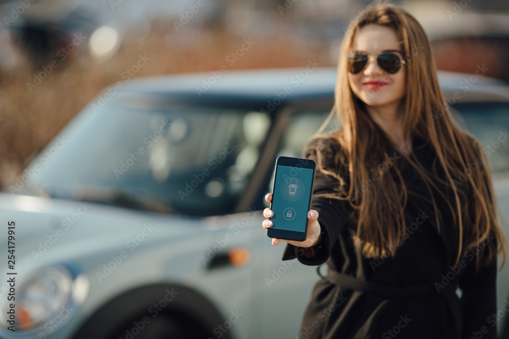 Woman using Smartphone near the car. Mobile phone apps for car owners concept.