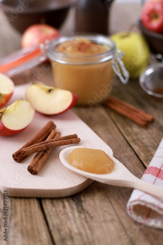 fresh homemade apple jam , apple puree, with cinnamon, fresh apples and a wooden spoon on wooden rustic table