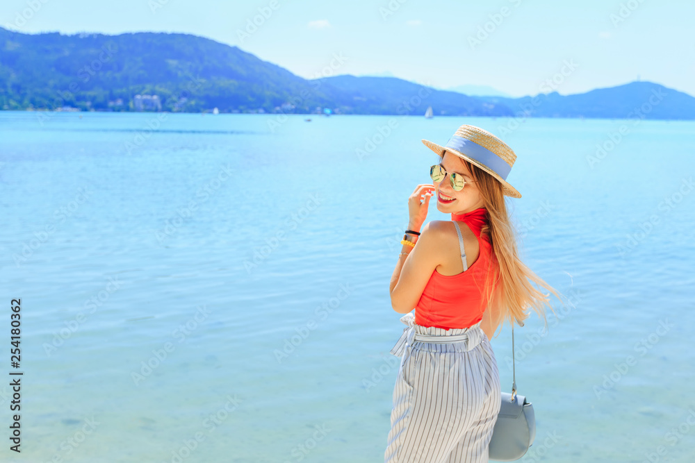 stylish young woman smiles near lake and mountains on travel vac stylish young woman smiles near lake and mountains on travel vac