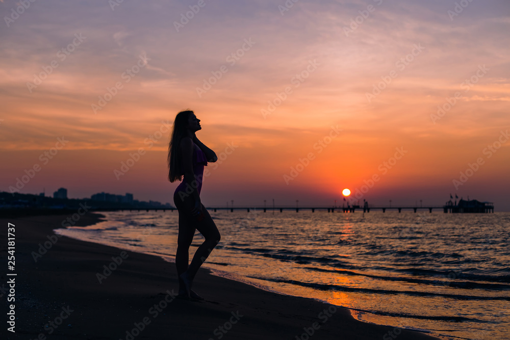 silhouette girl with long hair and fit body posing on the beach
