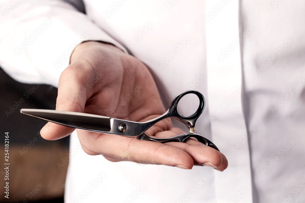 Barber scissors in male hands, barber shop. Background for male salon, hairdresser.