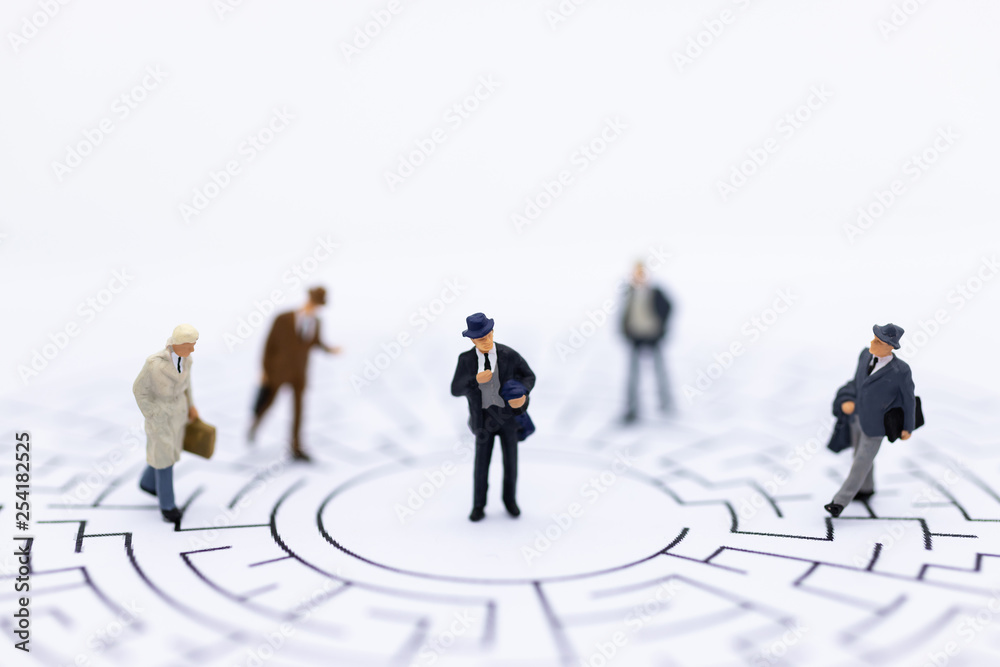 Miniature people : Businessmen standing on maze map and looking for a solution with teamwork. Image use for solve problems and new idea concept. Miniature people : Businessmen standing on maze map and looking for a solution with teamwork. Image use for solve problems and new idea concept.