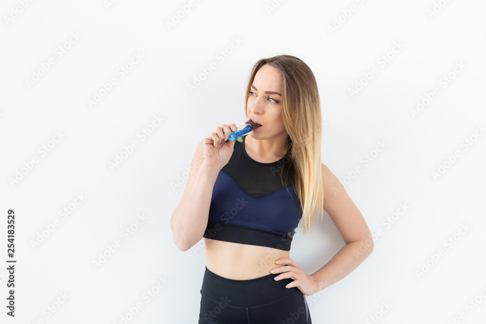 Attractive sporty fitness woman holding a protein bar on white background Attractive sporty fitness woman holding a protein bar on white background