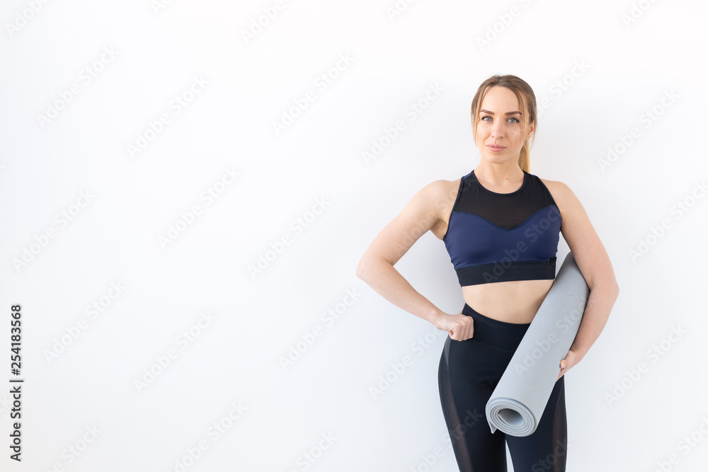 People, fitness and sport concept - Attractive and healthy woman holding grey mat over white background with copy space People, fitness and sport concept - Attractive and healthy woman holding grey mat over white background with copy space
