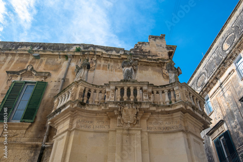 Lecce, Puglia, Italy - Medieval street and historical center in the old town. View and detail of an ancient gate or door, statues and facade of houses. A region of Apulia