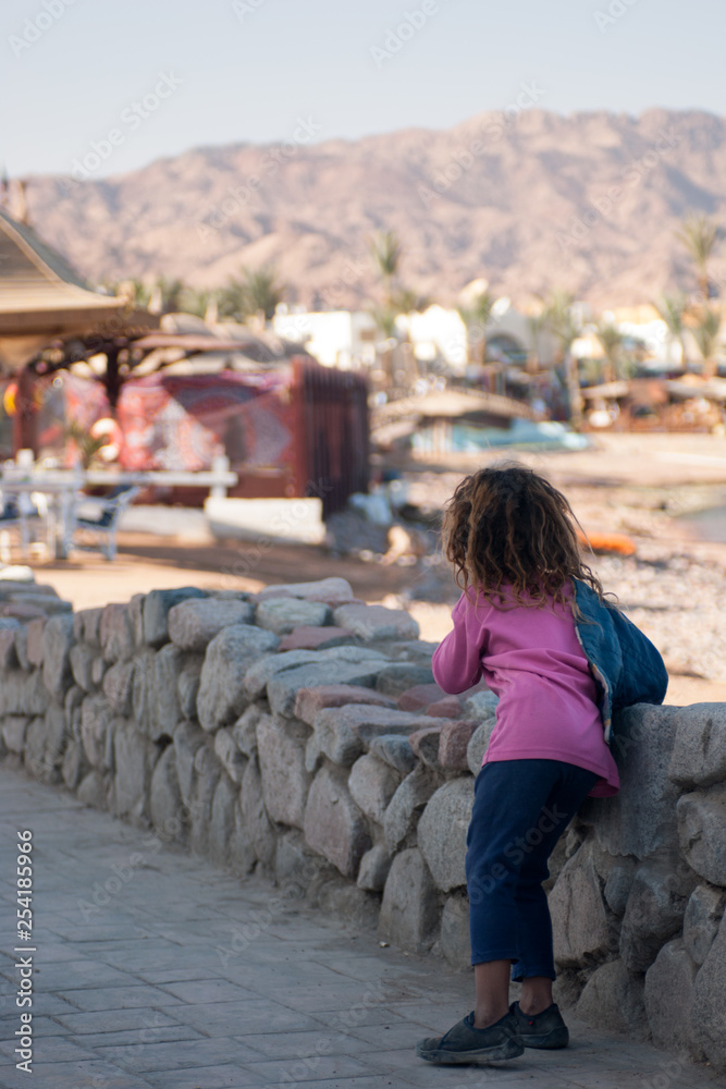 Fototapeta premium Arab girl standing on the promenade of Dahab back to the photographer