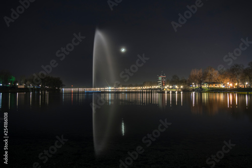 fountain on the lake ada with the moon in the background and lighting