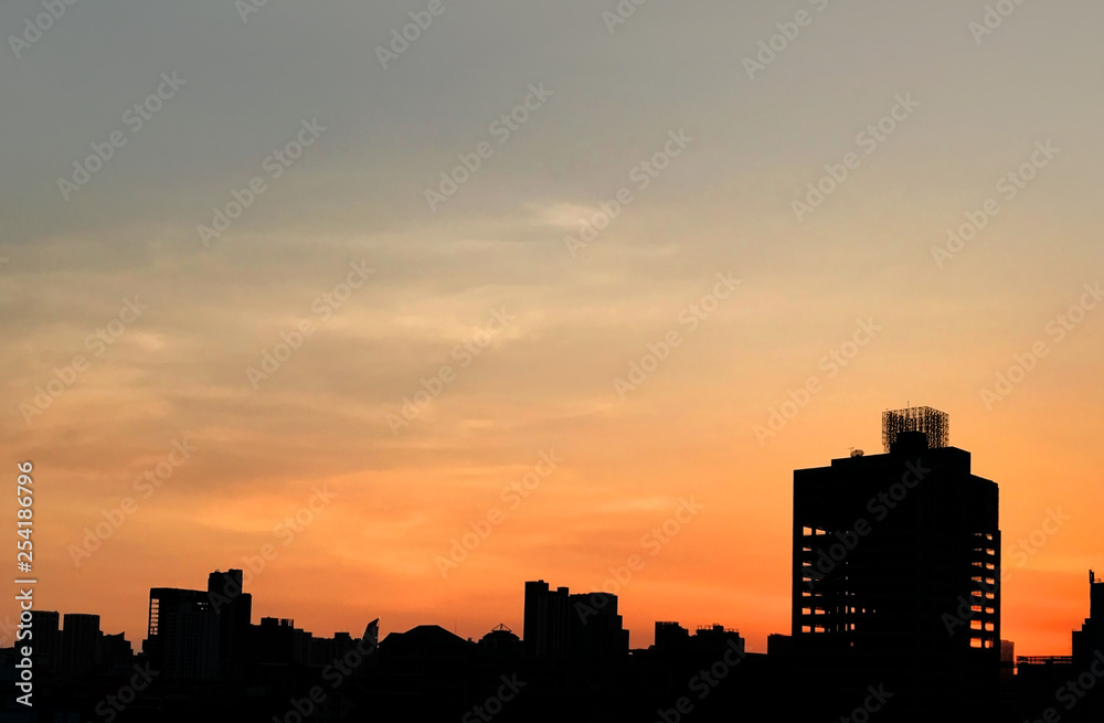 Silhouette of buildings in Asia city with evening sunset and orange sky background.