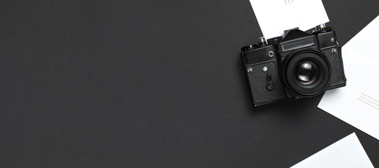Old retro vintage camera, white blank photo cards on black background top view flat lay with copy space. Concept for the photographer, old photographic equipment, minimalistic style selective focus