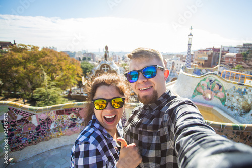 Photography Funny young couple looking at camera taking photo with smart phone smiling in Park Guell, Barcelona, Spain