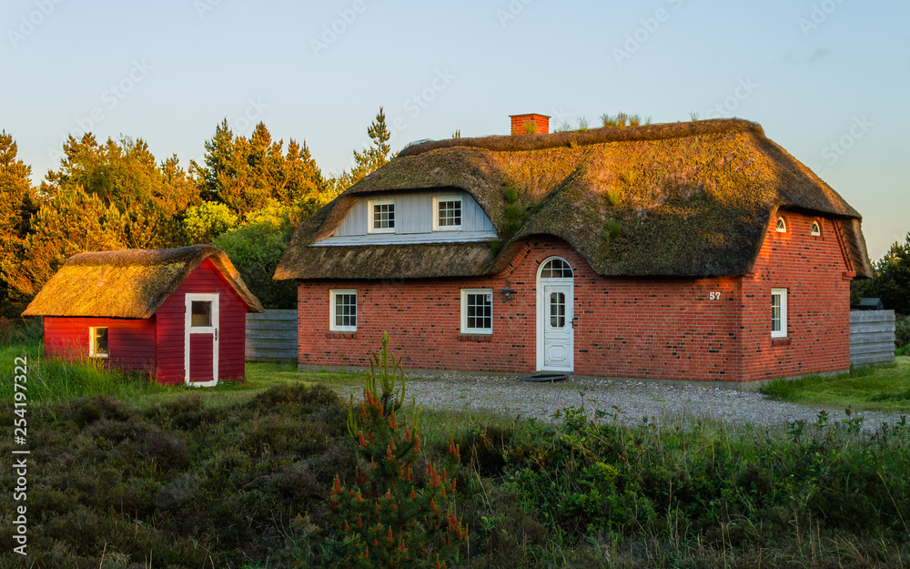 Panoramic view of a traditionally brick built house, thatched roof and small cottage. Beautiful Scene of holiday home in the near of the north sea during sunset. Romo, Tonder, Denmark, Europe
