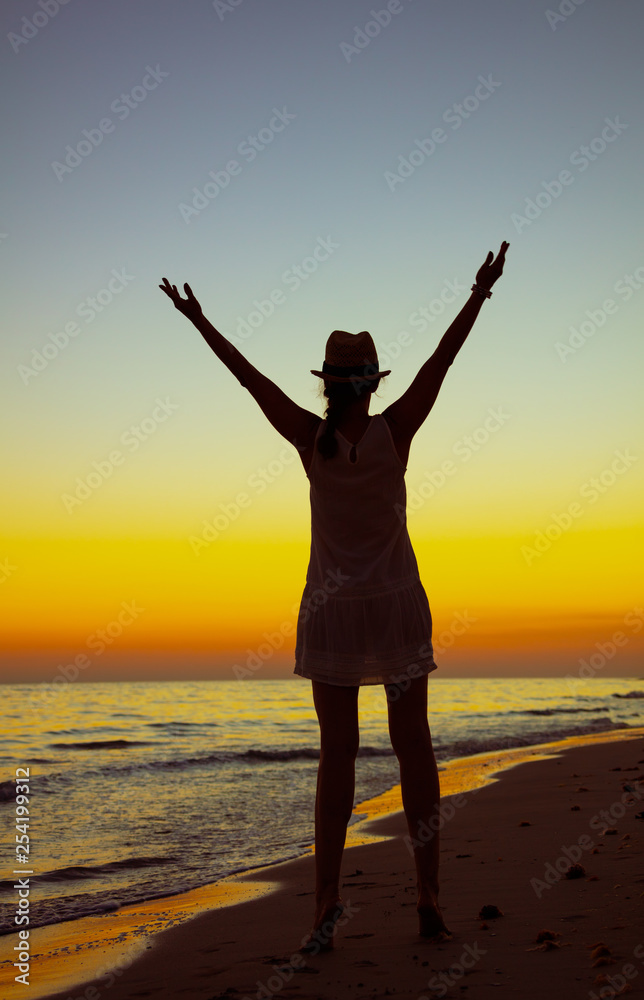 healthy tourist woman on ocean coast at sunset rejoicing