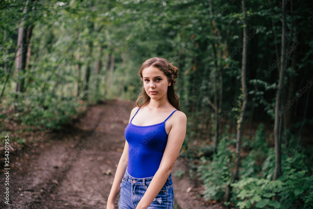 Beautiful girl in short shorts and a blue T-shirt in the woods Beautiful girl in short shorts and a blue T-shirt in the woods