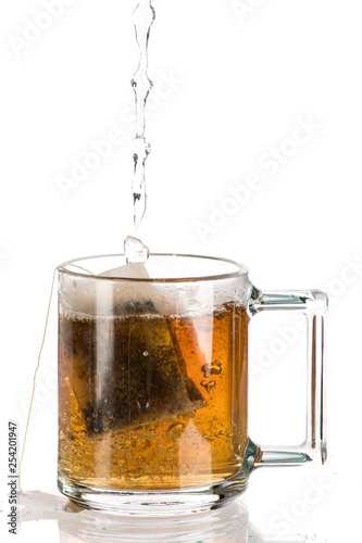 Making tea with sugar from a tea bag in a transparent mug on a white background