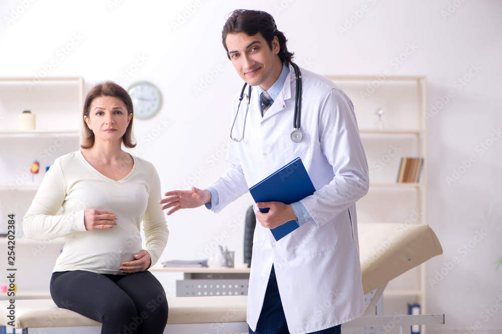 Fototapeta premium Old pregnant woman visiting young male doctor 