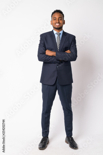 Full body shot of happy young African businessman with arms crossed